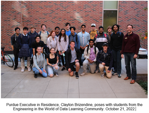 a group of students poses with Executive in Residence Clayton Brizendine outside in front of a brick wall