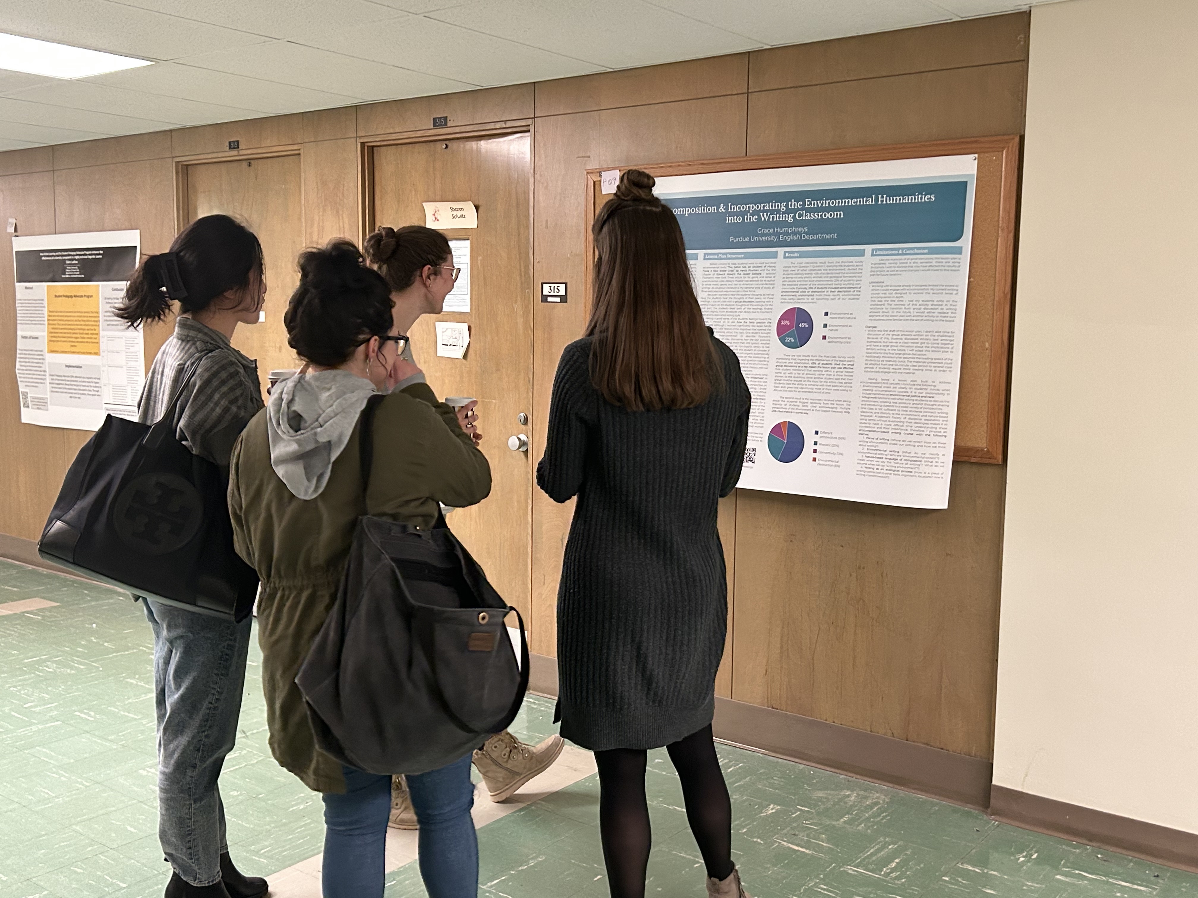 Four instructors stand in front of a poster discussing its content.