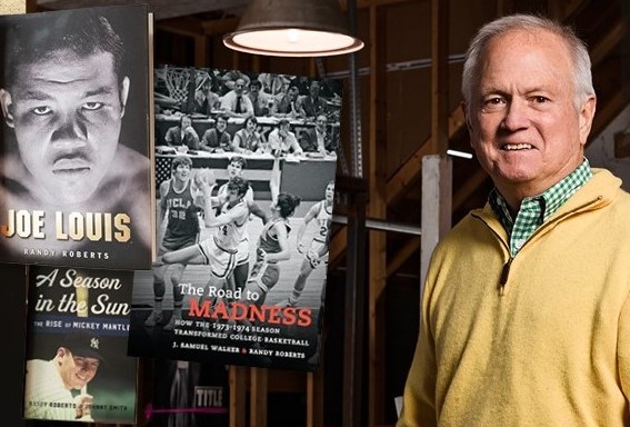 Randy Roberts standing next to a display of his books, including "Joe Louis: A Season in the Sun" and "The Road to Madness."