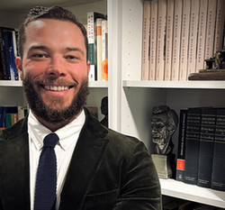 Professor Jonathan Lande stands in front of a bookcase 