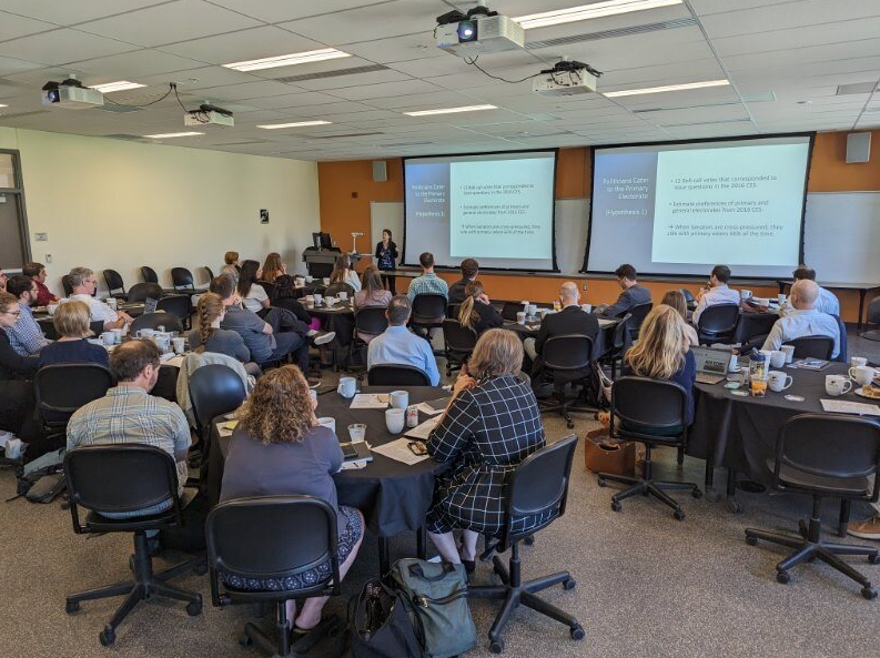 Professor presenting research to attendees at a conference.