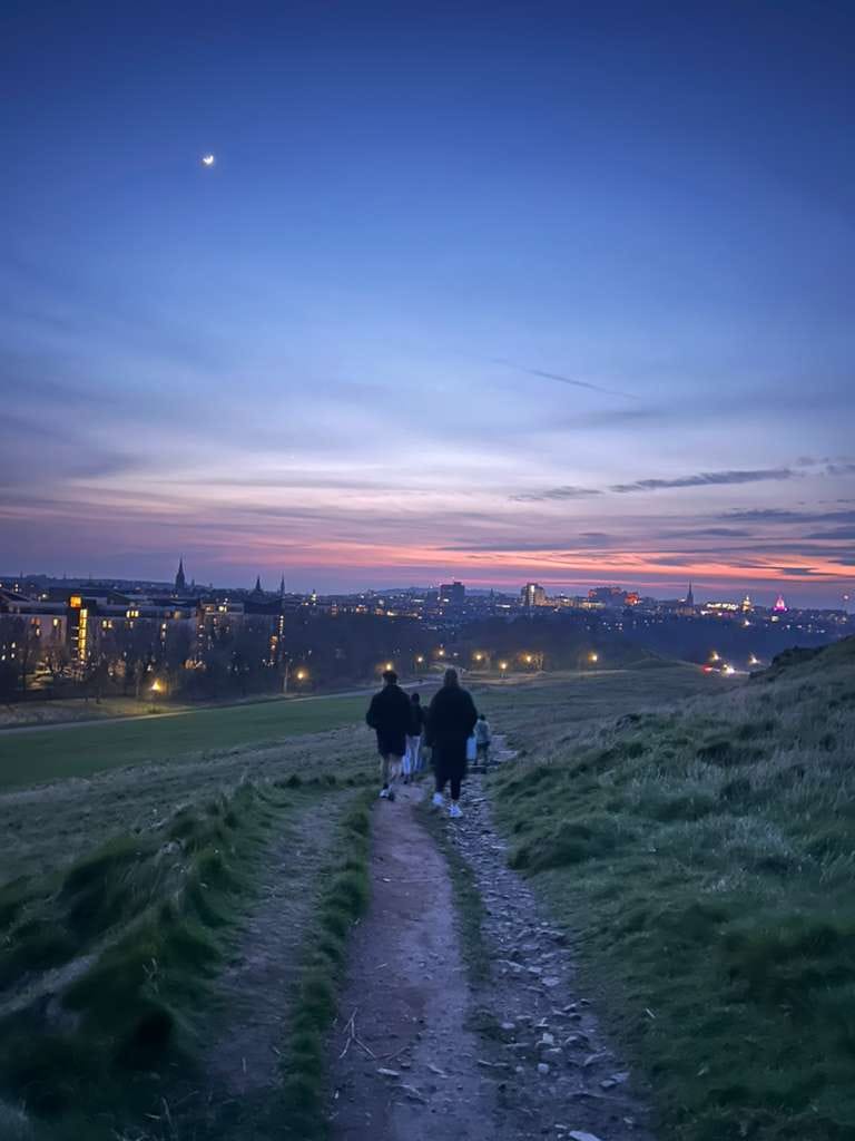 Students walking down a hill in Edinburgh at sunset