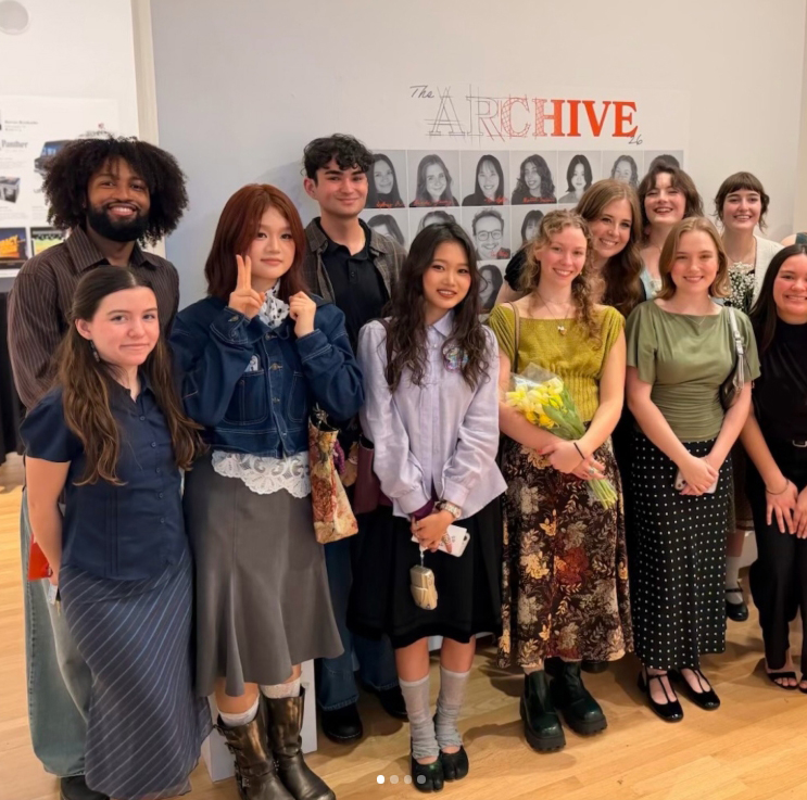 Students stand in front of the title wall for their senior show