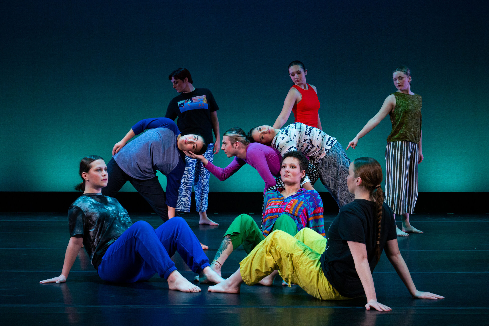 Group of dancers in colorful costumes in a staged pose on stage