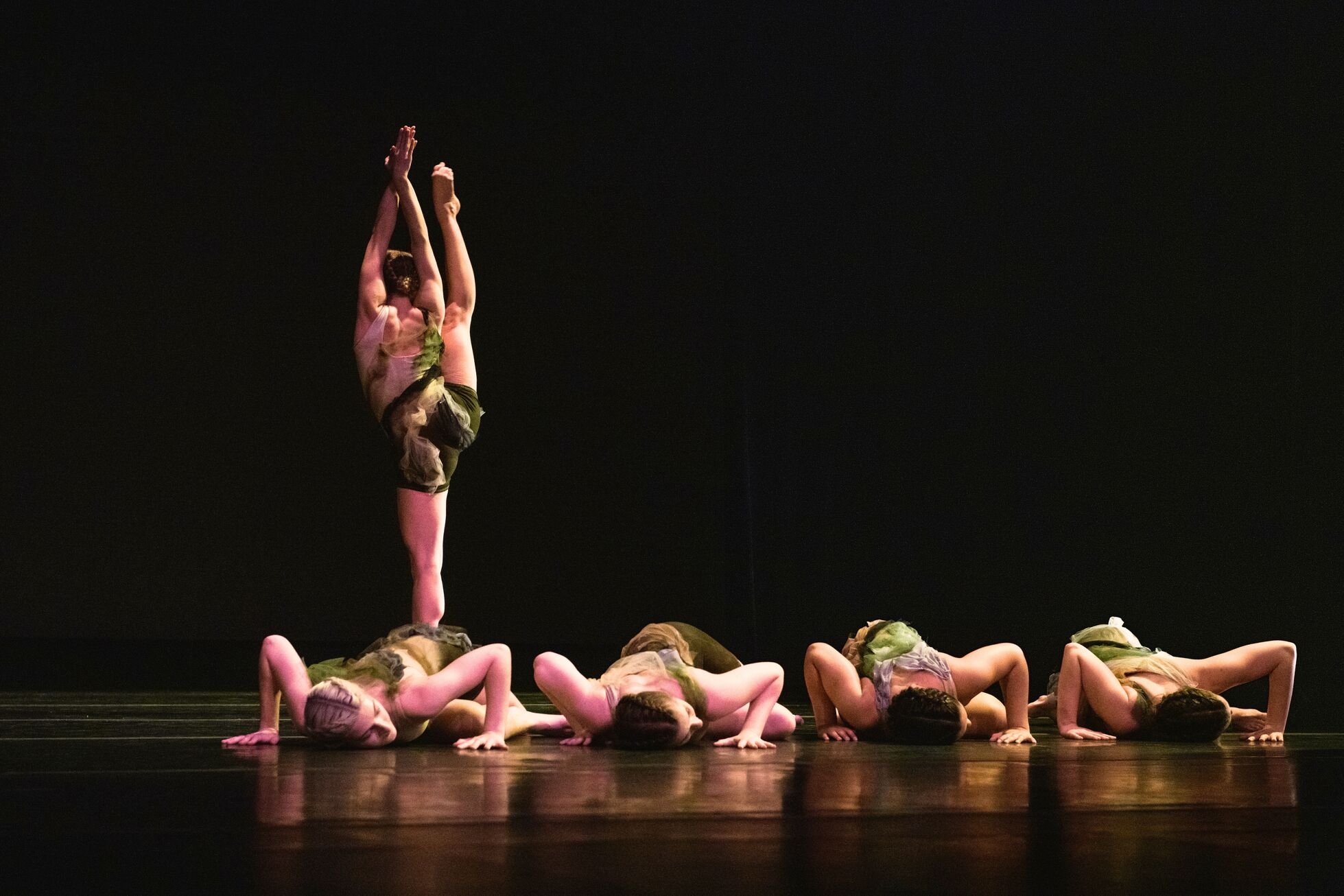Dancers on stage. Four dancers on the flour, one standing.