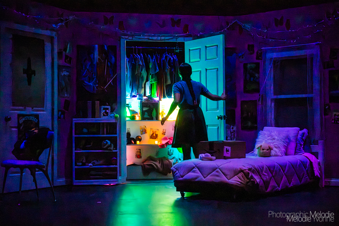 Stage production, girl looking into glowing closet.