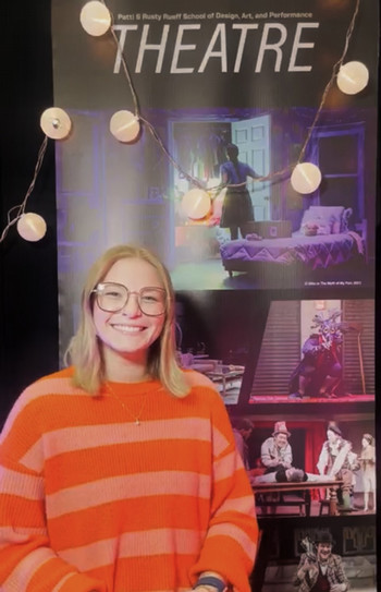 Ellie Jones sitting in front of a Theatre banner waiting for her student interview.