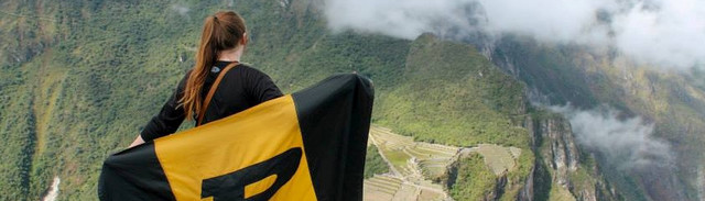 student facing mountains with purdue flag across their back 