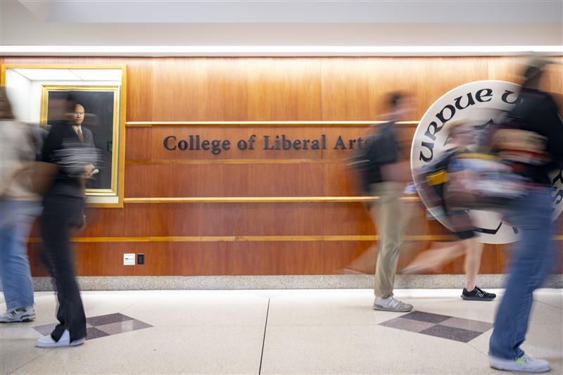 Students walking by a College of Liberal Arts sign.
