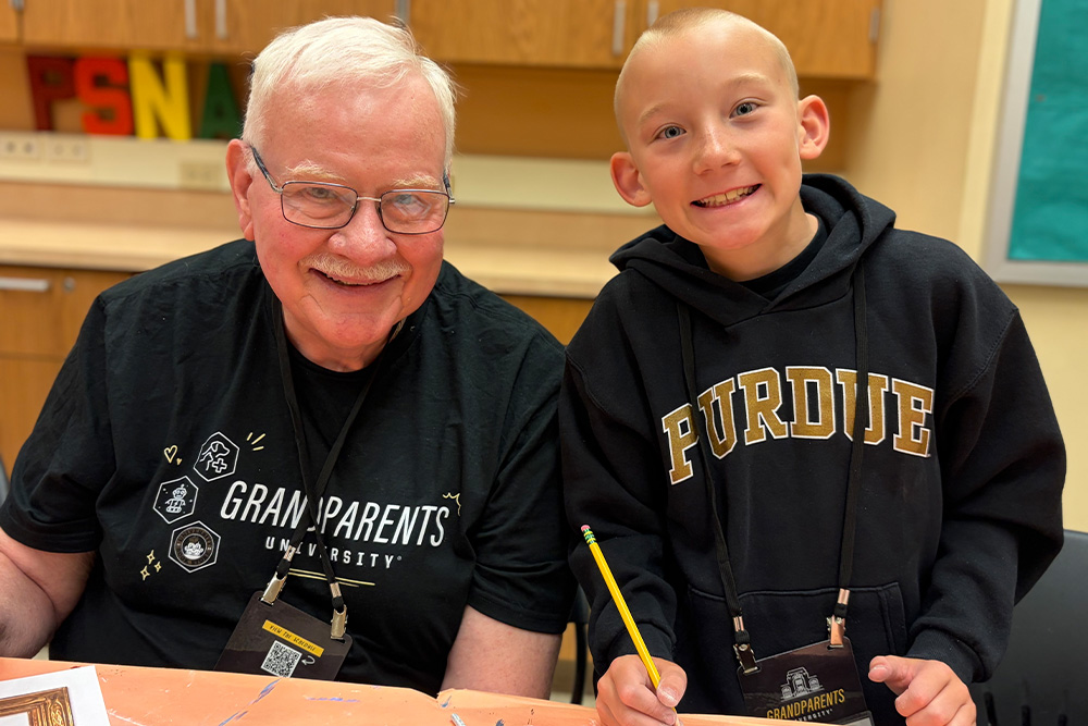 A grandfather and his grandson sitting together at a table, sketching their future sculptures.