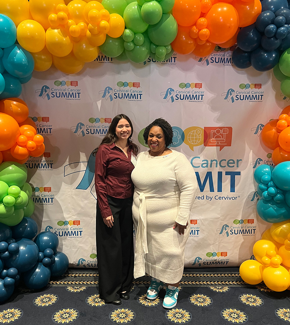 Johari posing in front of a balloon arch at an event with a co-worker at her internship.