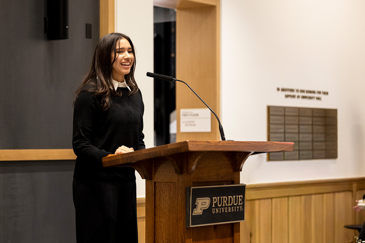 Johari standing at a podium with the Purdue logo on the front.