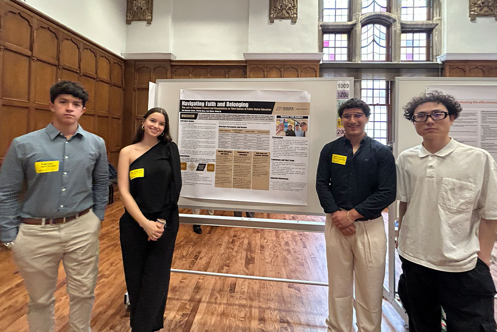 Four CLA students standing next to their display at the annual Spring Undergraduate Research Conference