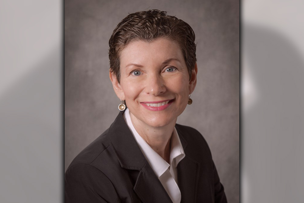 Headshot of Susan Brock Williams in a blazer against a gray backdrop.