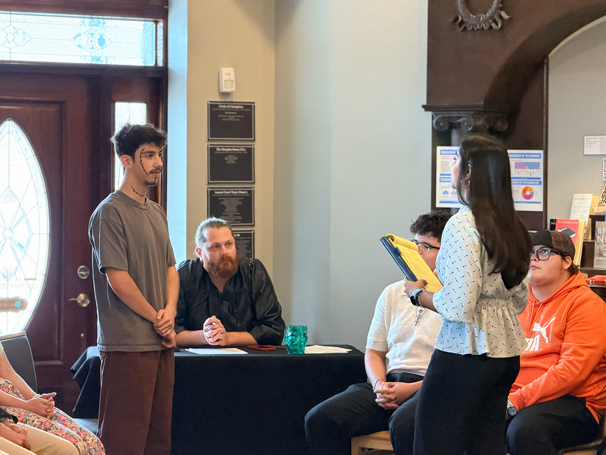 One student dressed as Frankenstein’s creature while another stands across from him holding a padfolio.