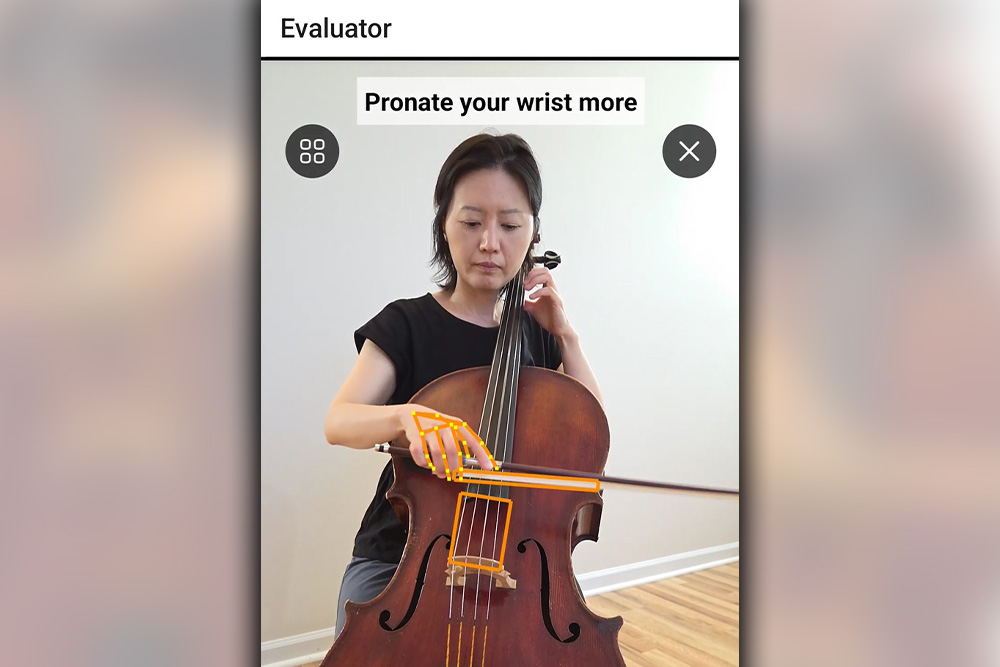 A woman playing a cello with yellow highlights on her wrist with instructions from AI that say “pronate your wrist more”