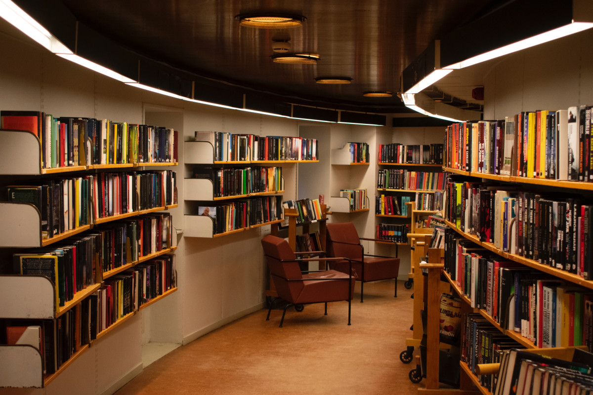 A wide, curved library aisle with chairs.