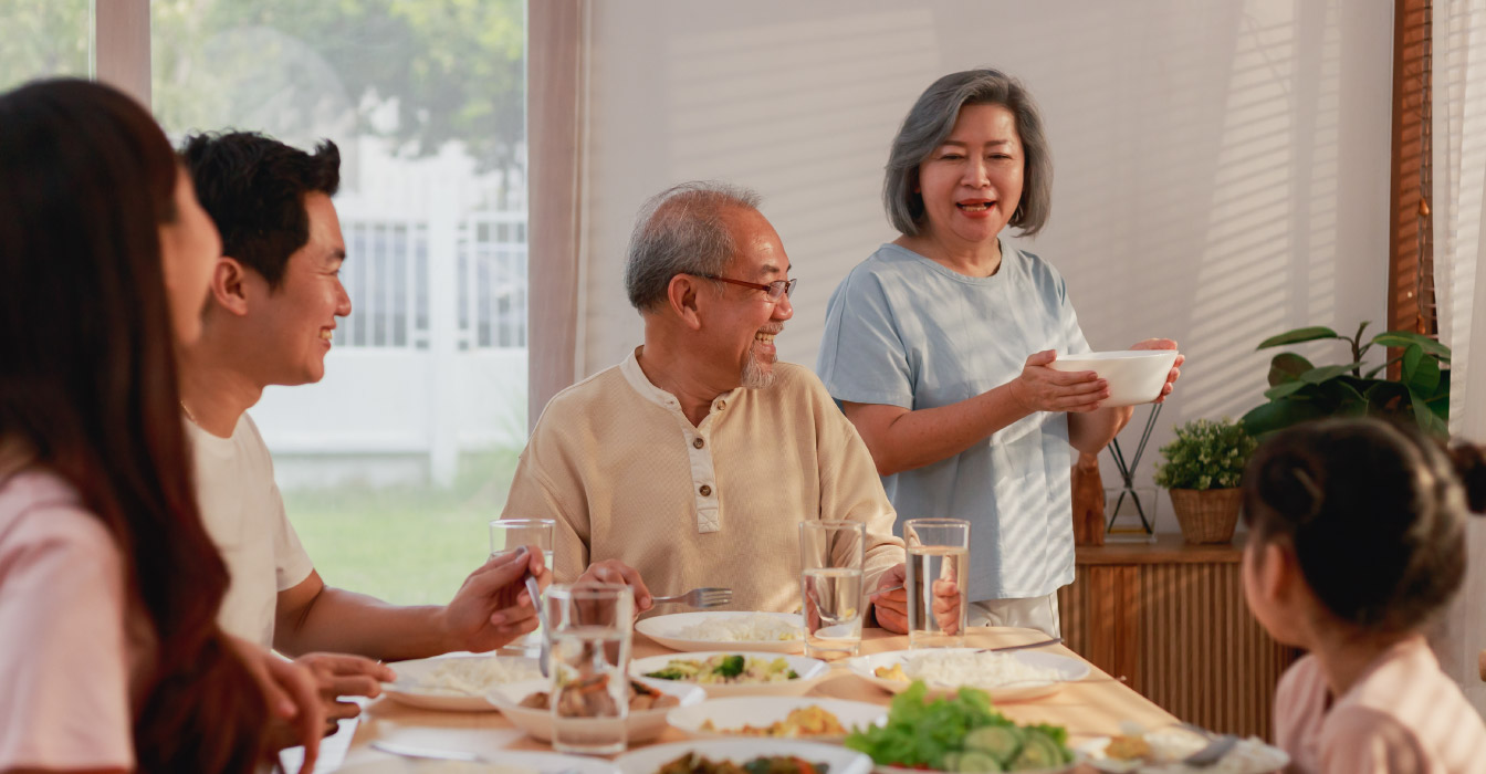 A family sitting around a dinning room table preparing to eat.