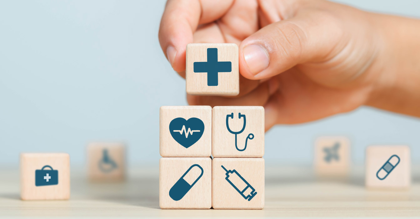 A hand putting multiple wooden blocks with medical icons on them onto a table.