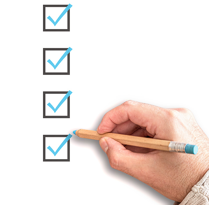 A hand holding a pencil marking checkboxes.