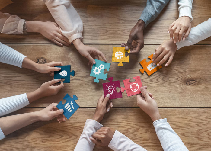 Several hands holding puzzle pieces arranged in a circle.