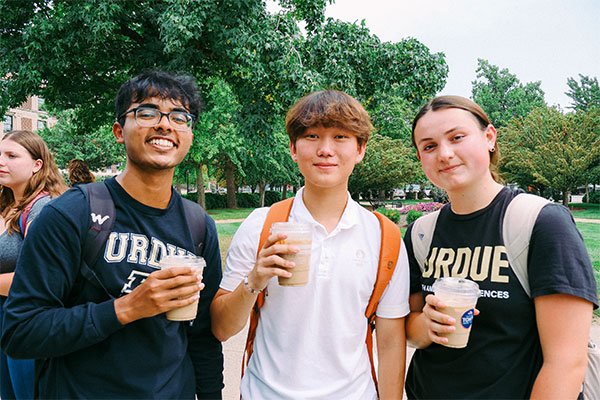 Three students smiling and looking at the camera.