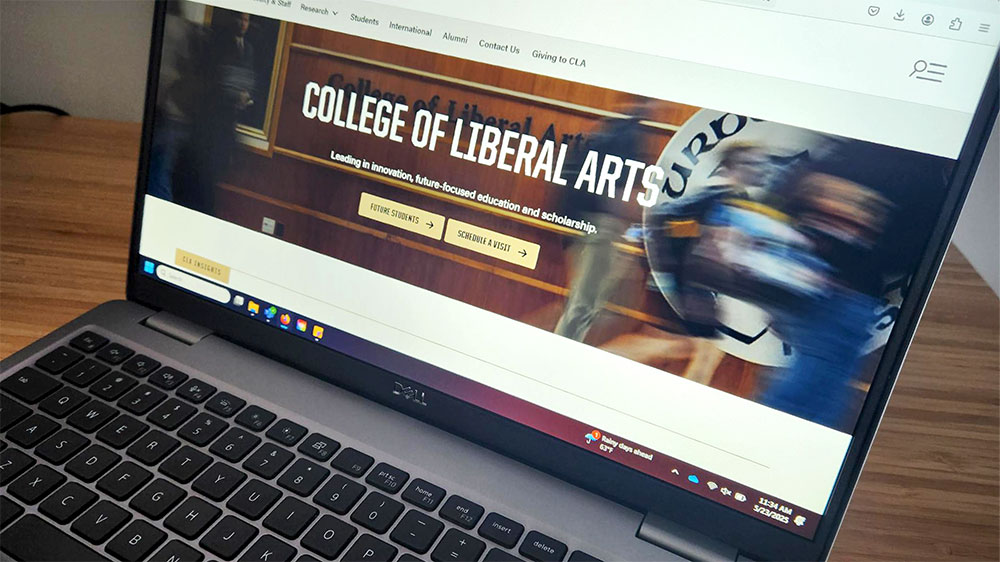 An open laptop prominently displaying the College of Liberal Arts homepage