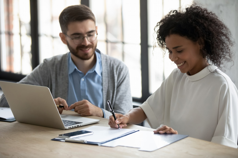 Two people sitting at a table with on taking notes while an advisor talks to them