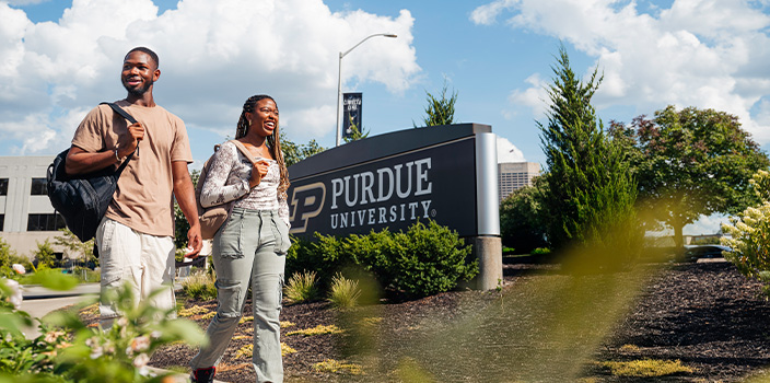 Two students walking in front of a Purdue sign