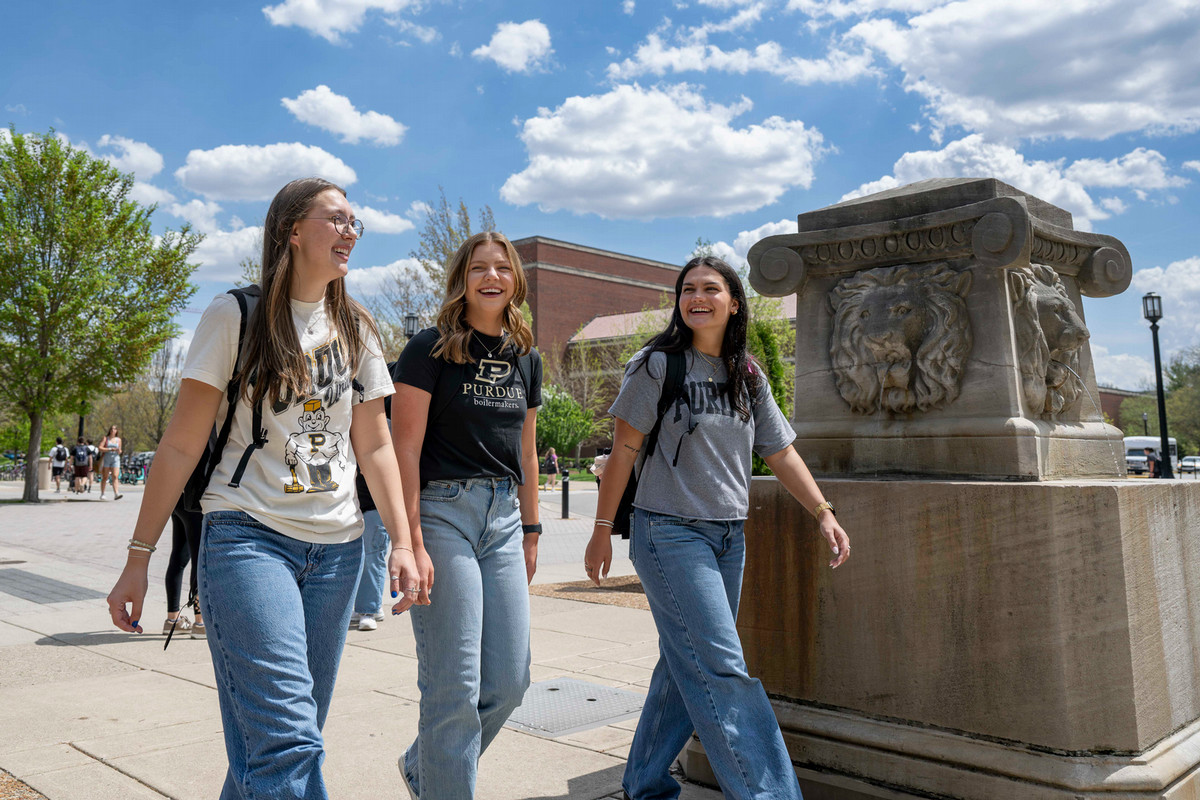 Three Purdue students walking outside near a fountain