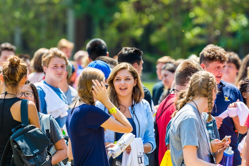 Multiple students talking together while standing outside on a sunny day