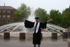 Student with Cap and Gown in Founders Park 