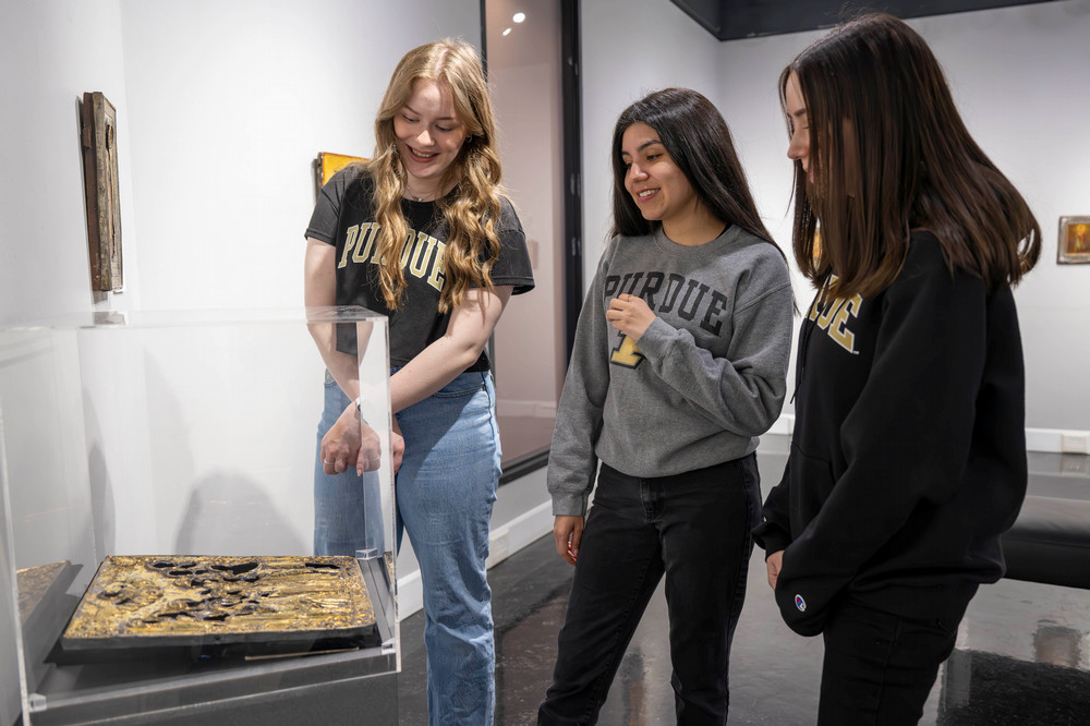 Three Purdue University students looking at an art exhibit